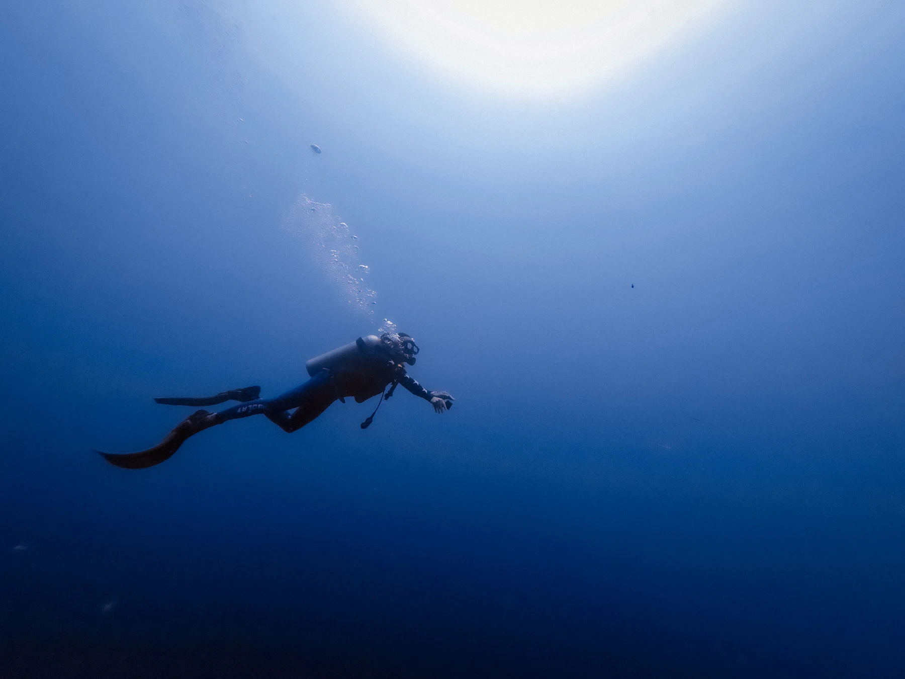 Mergulhador descendo no azul profundo